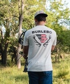 Man wearing a 'Burlebo' t-shirt with an American flag design in a forest setting