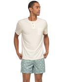 Man wearing a white henley shirt and light green shorts with a subtle pattern on a white background