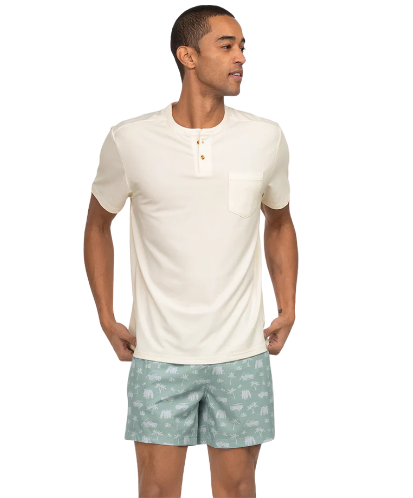 Man wearing a white henley shirt and light green shorts with a subtle pattern on a white background