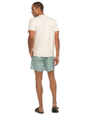 Man wearing a white henley t-shirt and green patterned shorts on a white background