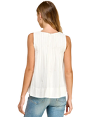 Woman wearing a white sleeveless top and blue jeans on a white background