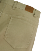 Close-up of olive green pants with a GenTeal brand label on a white background