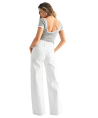 Woman wearing a gray top and white pants on a white background