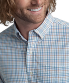 Man wearing a blue and white checkered shirt with a blurred background