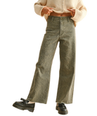 Person wearing green patterned pants and a beige cropped top on a white background