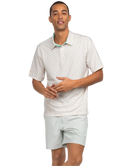 Man wearing a patterned short-sleeve shirt and light gray shorts on a white background