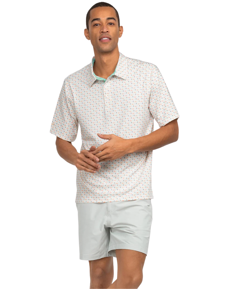 Man wearing a patterned short-sleeve shirt and light gray shorts on a white background