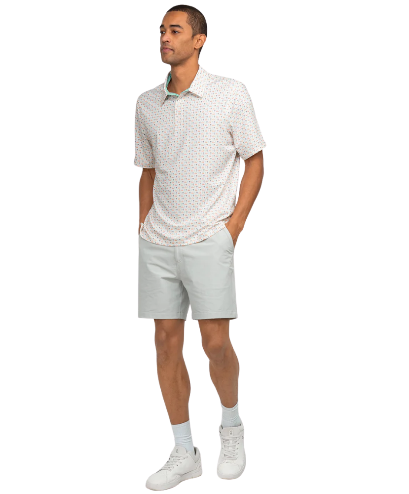 Man wearing a patterned white shirt and light gray shorts on a white background