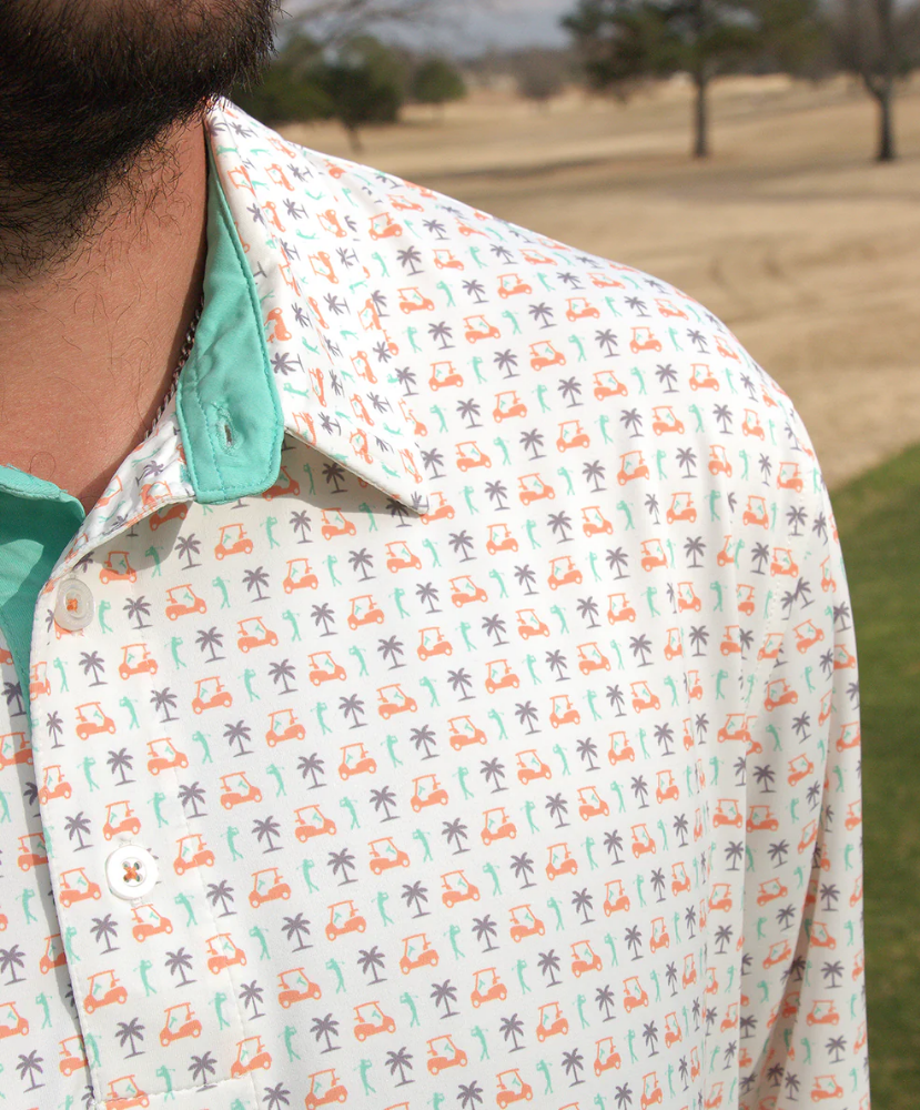 Close-up of a patterned shirt with golf cart and palm tree design on a blurred outdoor background.