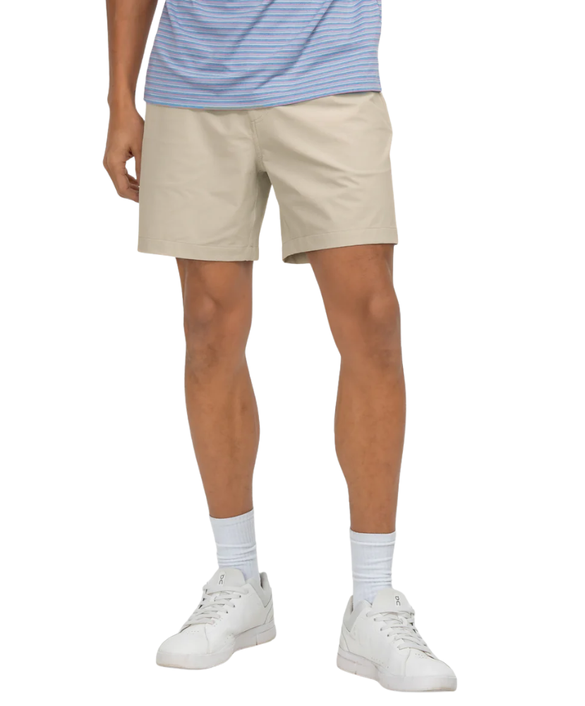 Person wearing beige shorts, a striped shirt, white socks, and white sneakers on a white background