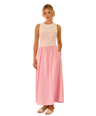 Woman wearing a sleeveless dress with a cream top and pink skirt on a white background