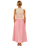 Woman wearing a two-tone dress with a beige top and pink skirt on a white background