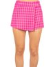 Woman wearing a pink houndstooth skort on a white background