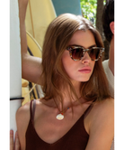 Woman wearing Krewe sunglasses with a blurred background