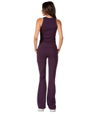 Woman wearing a purple tank and pants athleisure set outfit on a white background
