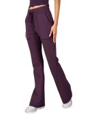 Woman wearing a purple tank and pants athleisure set outfit on a white background