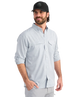 Man wearing a light blue performance HUK button-up shirt and black cap on a white background