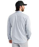 Man wearing a light blue performance HUK button-up shirt and black cap on a white background