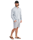 Man wearing a light blue performance HUK button-up shirt and black cap on a white background