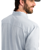 Man wearing a light blue performance HUK button-up shirt and black cap on a white background
