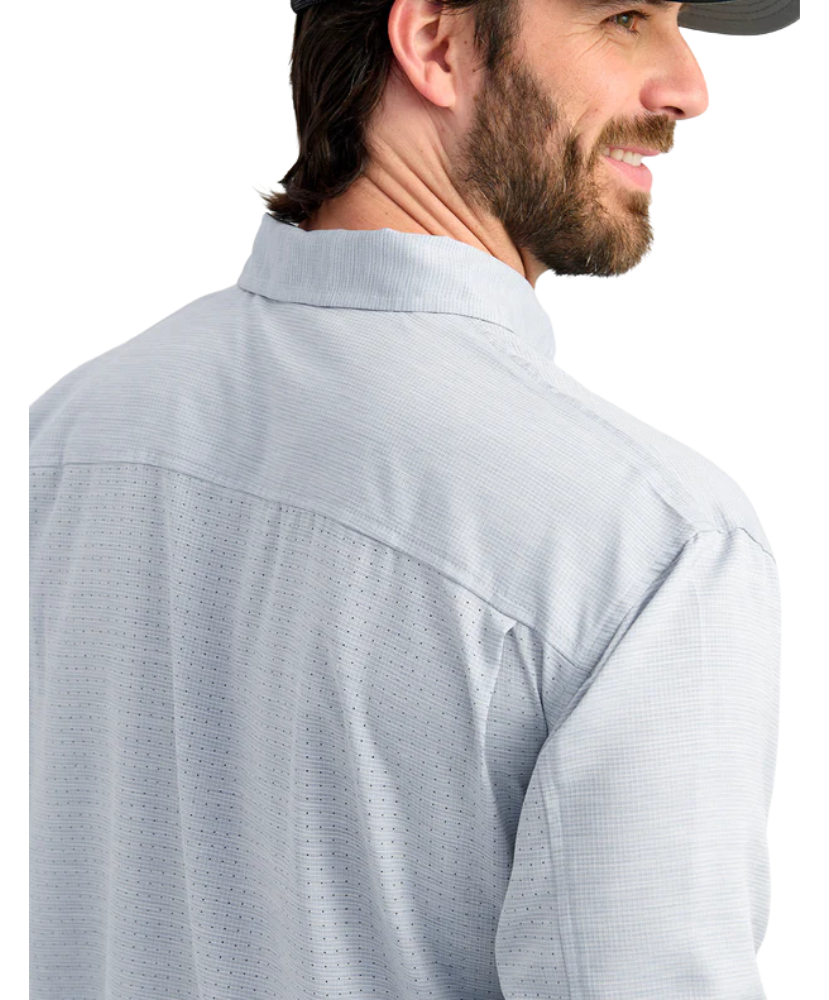 Man wearing a light blue performance HUK button-up shirt and black cap on a white background