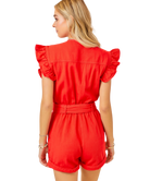 Red romper with ruffled sleeves worn by a person on a white background