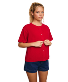 Woman wearing a red cardigan sweater and blue shorts on a white background