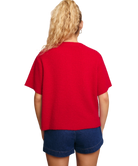 Woman wearing a red cardigan sweater and blue shorts on a white background
