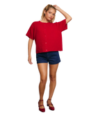 Woman wearing a red cardigan sweater and blue shorts on a white background