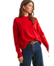 Woman wearing a red sweater and blue jeans on a white background