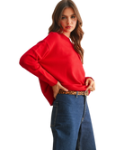 Woman wearing a red sweater and blue jeans on a white background