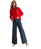 Woman wearing a red sweater and blue jeans on a white background