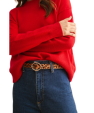 Person wearing a red sweater and blue jeans with a leopard print belt on a white background