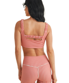 Woman wearing a red and white GINGHAM checkered tsports bra on a white backgrounD