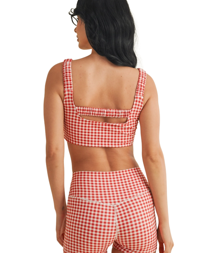 Woman wearing a red and white GINGHAM checkered tsports bra on a white backgrounD