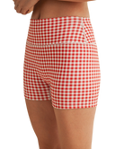 Woman wearing a red and white gingham checkered shorts on a white background
