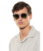 Man wearing krewe sunglasses and a light gray shirt on a white background