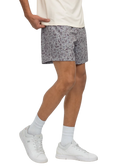 Person wearing a white t-shirt, CAMO patterned shorts, and white sneakers on a white background