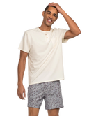 Man wearing a beige shirt and CAMO patterned shorts on a white background