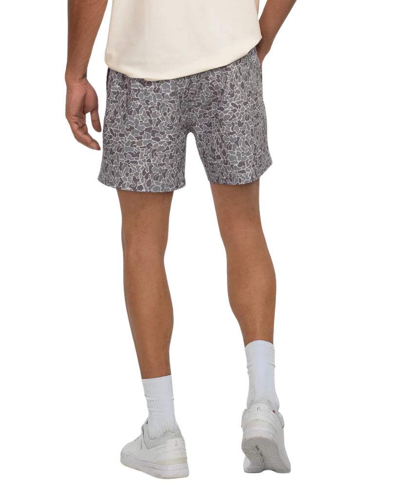 Person wearing CAMO patterned shorts on a white background