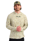Man wearing a sand camouflage hoodie with 'Huk' branding on a white background