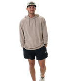 Man wearing a beige hoodie and black shorts on a white background