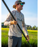Man wearing a sand camouflage hoodie with 'Huk' branding on a white background