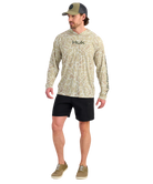 Man wearing a sand camouflage hoodie with 'Huk' branding on a white background