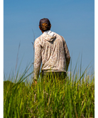 Man wearing a sand camouflage hoodie with 'Huk' branding on a white background