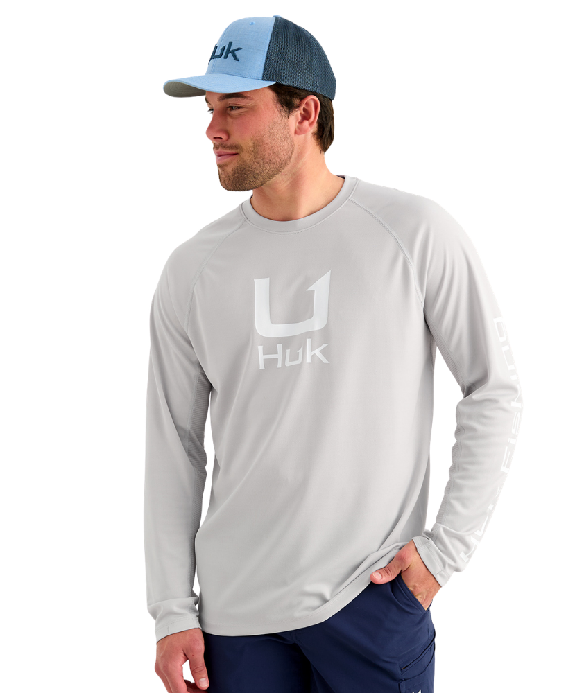 Man wearing a gray long-sleeve shirt with Huk logo and a matching cap on a white background