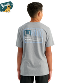 KID wearing a gray HUK t-shirt with a logo on the back, standing against a white background.