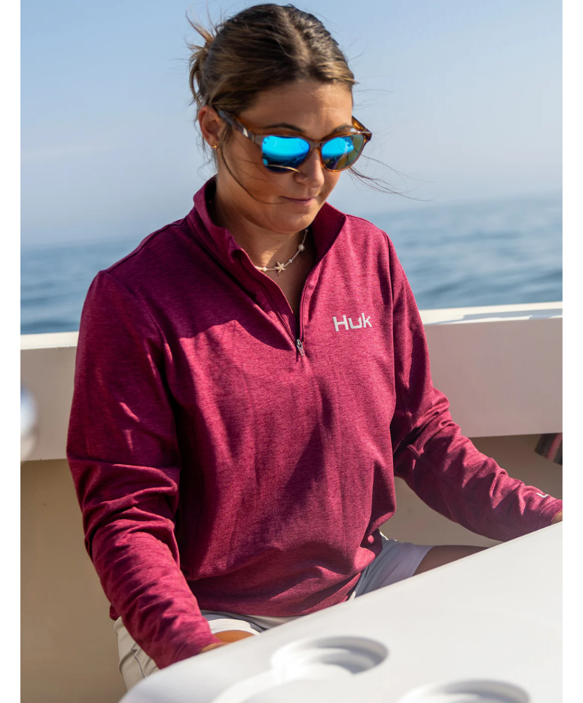 Woman wearing a maroon heather Huk pullover on a white background