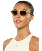 Woman wearing Krewe sunglasses with a plain background