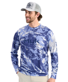 Man wearing a blue camouflage long-sleeve shirt with HUK logo on a white background
